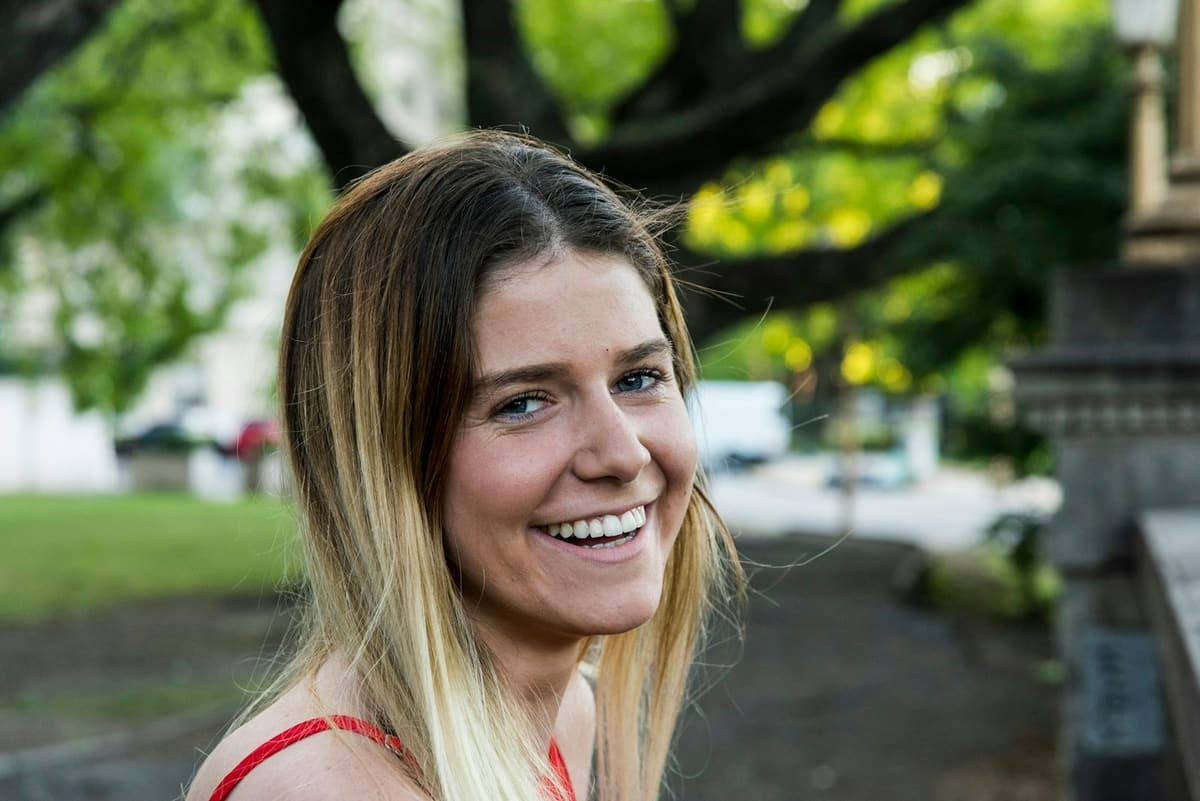 Mujer joven con una sonrisa blanca y natural al aire libre